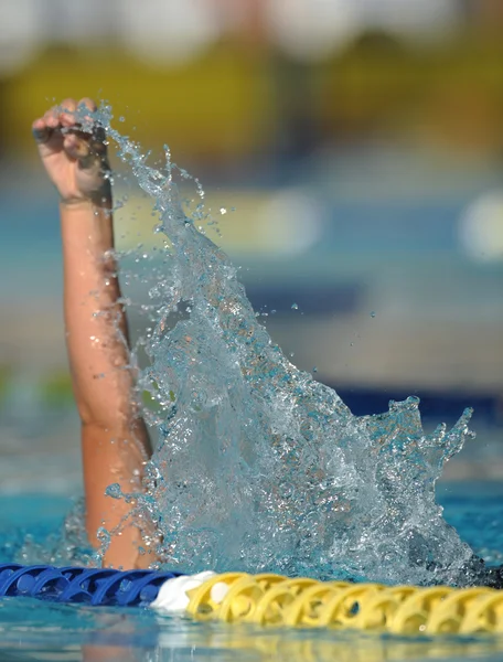 Swimmer\'s arm reaches out of the pool mid-stroke
