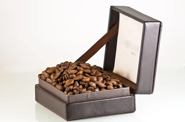 Broun leather box full of coffee seeds isolated