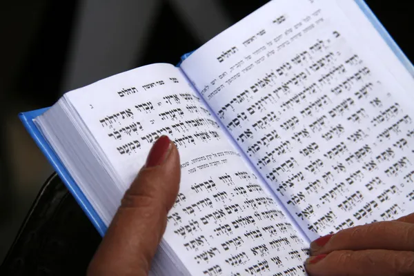 Biblia hebrea abierta en manos de oración de mujer Imagen de stock