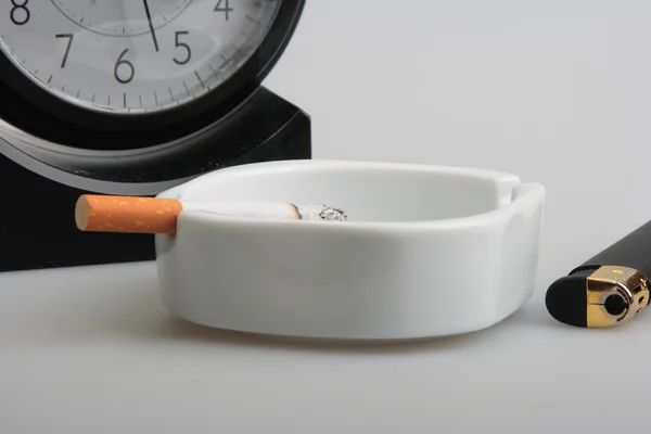 Zegar i biały popielniczka z papierosem — Zdjęcie stockowe