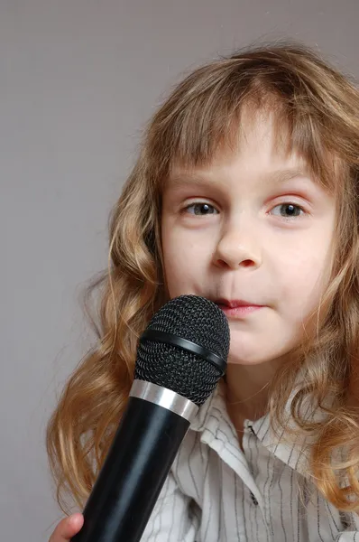 Söt liten flicka med svart mikrofon. — Stockfoto