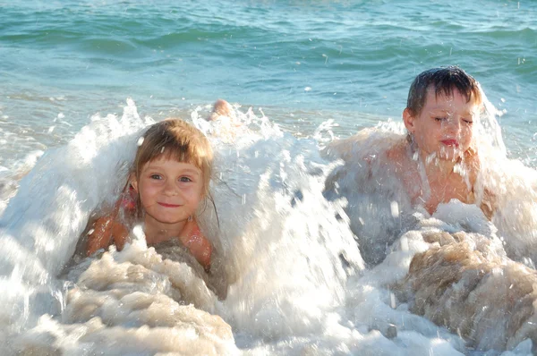 Niños en olas en la playa —  Fotos de Stock