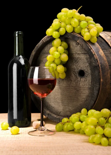 Červené víno a zelený hroznů na pozadí staré víno barel — Stock fotografie