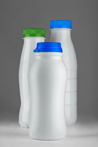 Trzy białe butelki na białym tle na szarym tle — Zdjęcie stockowe