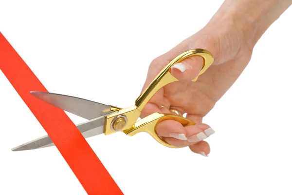 Tesoura em uma mão feminina corta uma fita vermelha — Fotografia de Stock