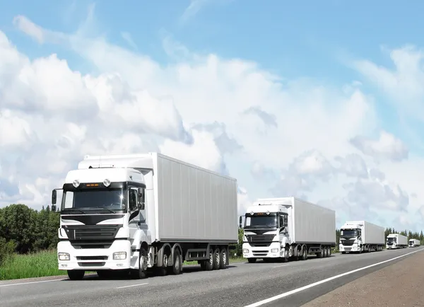 Caravan van witte trucks op highway Stockfoto
