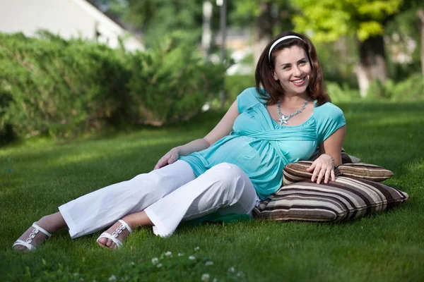 Mulher grávida bonita que põe na grama — Fotografia de Stock