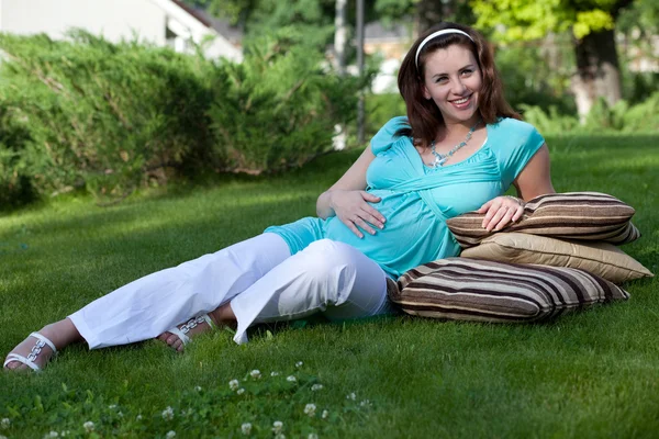 Mulher grávida bonita que põe na grama — Fotografia de Stock