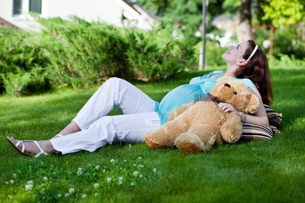 Beautiful pregnant woman relaxing on green grass — Stock Photo, Image