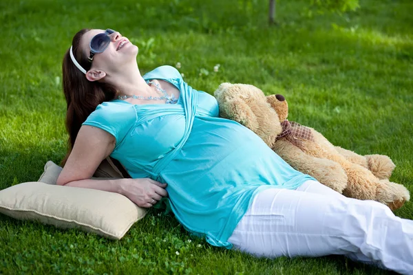 Beautiful pregnant woman relaxing on green grass — Stock Photo, Image