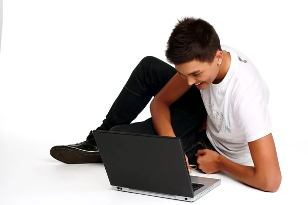Νεαρός άνδρας κάθεται και χρησιμοποιώντας ένα φορητό υπολογιστή — Φωτογραφία Αρχείου