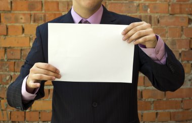 Business man holding a blank white sheet of paper clipart