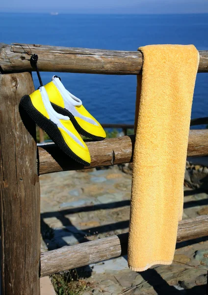 Asciugamano e scarpe da spiaggia su recinzione in legno — Foto Stock