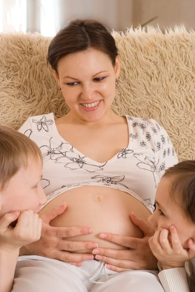 Los niños miran el estómago de la madre embarazada —  Fotos de Stock