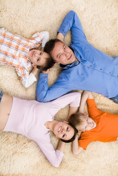 Família deitada no tapete — Fotografia de Stock