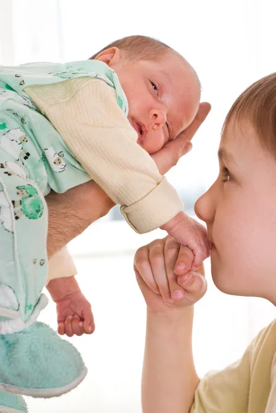 Chłopak całuje dłoń noworodka siostra — Zdjęcie stockowe