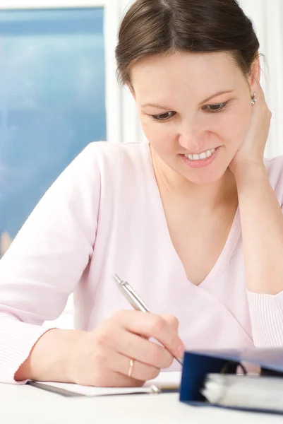 Woman sitting at a table and wrote — Stock Photo, Image