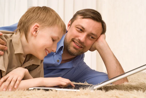 Отец и сын на ковре с ноутбуком — стоковое фото