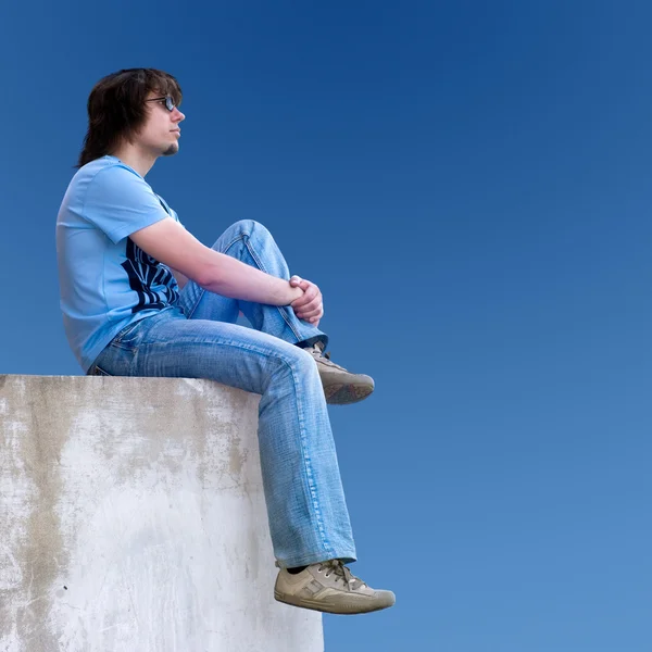 Young man sitting on the wall — Stock Photo, Image