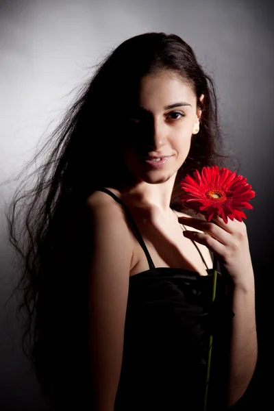 Attraktiv kvinna med röd blomma — Stockfoto
