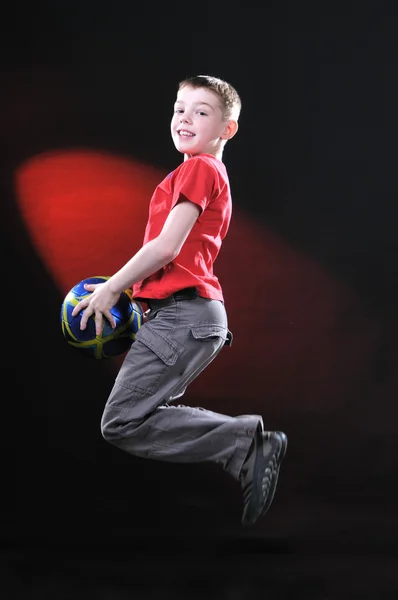 Menino no salto pega uma bola de futebol — Fotografia de Stock
