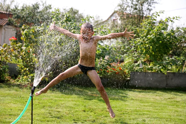 Saltando menino sob chuveiro de verão — Fotografia de Stock