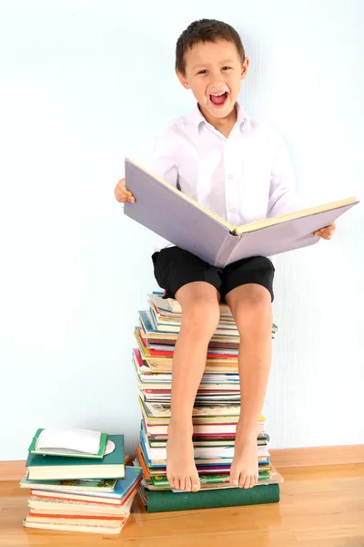 Schoolboy sitting on the heap of books — Stock Photo, Image