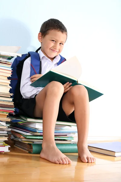 Schoolboy on the heap of books — Stock Photo, Image