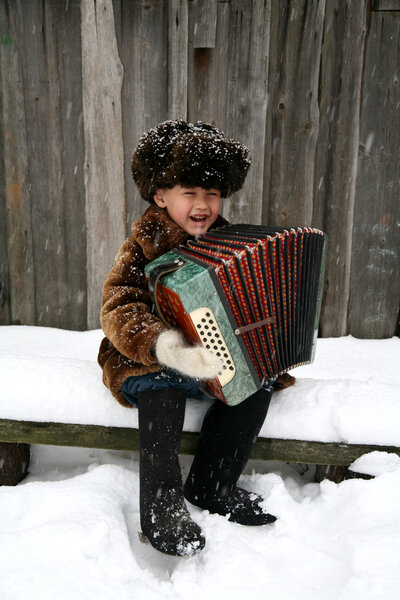 Boy with accordion under snowfall