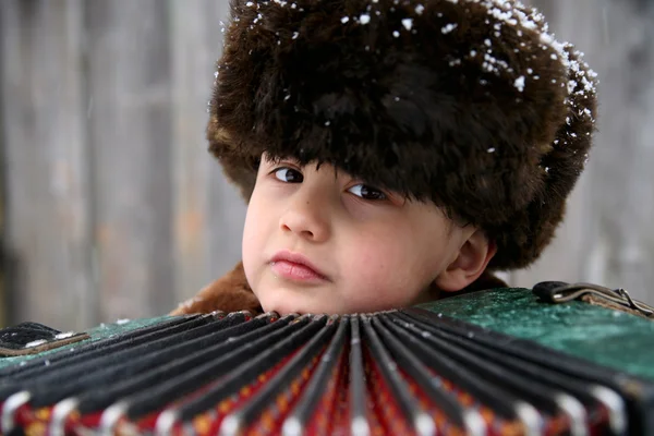 Boy with accordion under snowfall — Stock Photo, Image