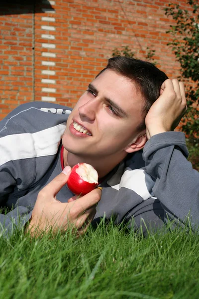 Adam tuğla duvarın yanında elma ile — Stok fotoğraf