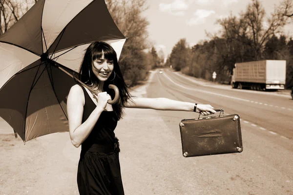 Автостопом девушка с винтажным чемоданом — стоковое фото