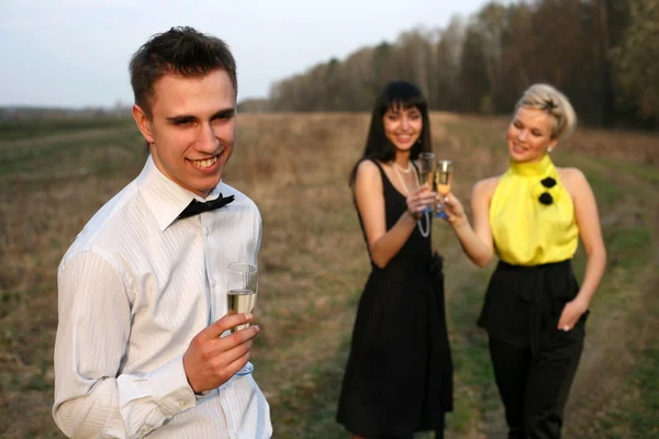 Две девушки и мужчина с вином — стоковое фото