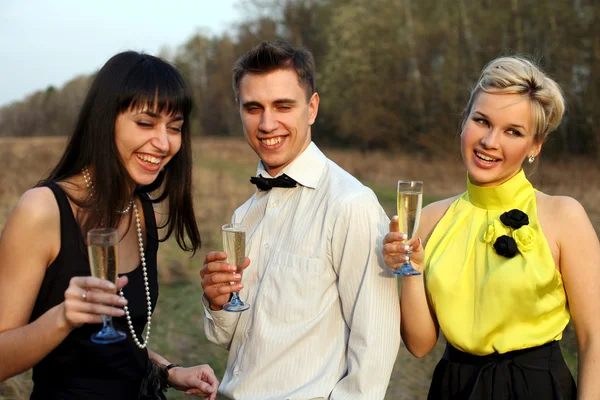 Две девушки и мужчина с вином — стоковое фото