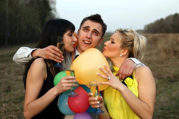 Due ragazza con vino baciare l'uomo all'aperto — Foto Stock