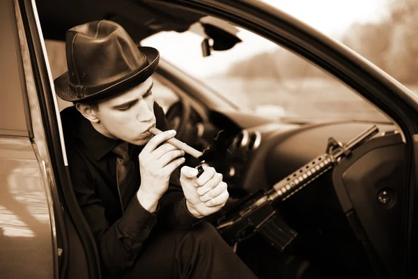 Man in car with cigar and rifle — Stock Photo, Image