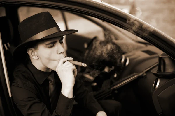 Man in car with cigar and rifle — Stock Photo, Image