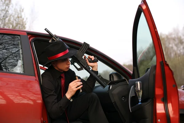 Mies autossa sikarin ja kiväärin kanssa — kuvapankkivalokuva