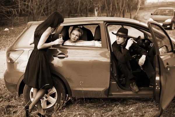 Två flickor, bil och man med gevär — Stockfoto