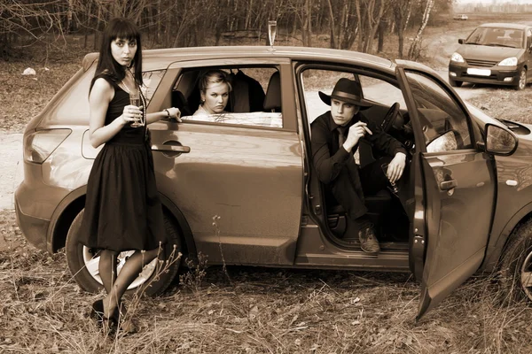 Zwei Mädchen, Auto und Mann mit Gewehr — Stockfoto