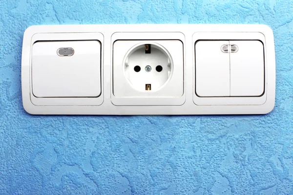 Electrical switch and plug in blue wall — Stock Photo, Image