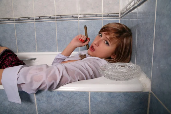 Блондинка в ванной в одежде с сигарой — стоковое фото