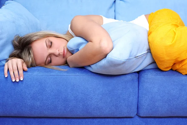 Mladá žena spí na modré pohovce — Stock fotografie