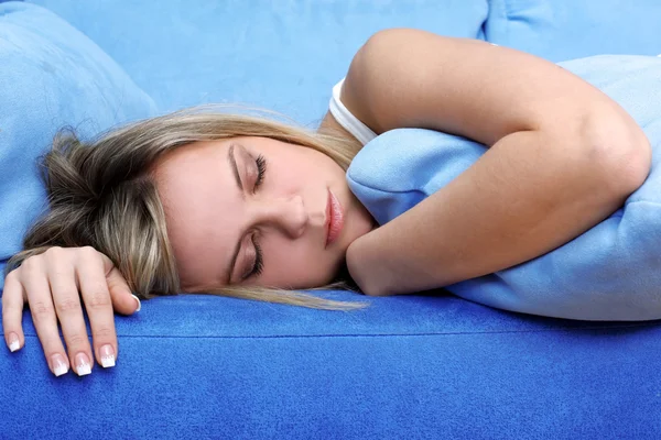Mujer joven durmiendo en sofá azul — Foto de Stock