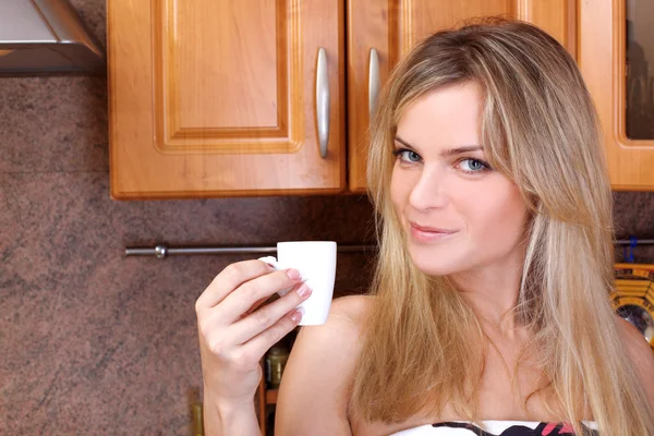 Женщина с горячим напитком на кухне — стоковое фото