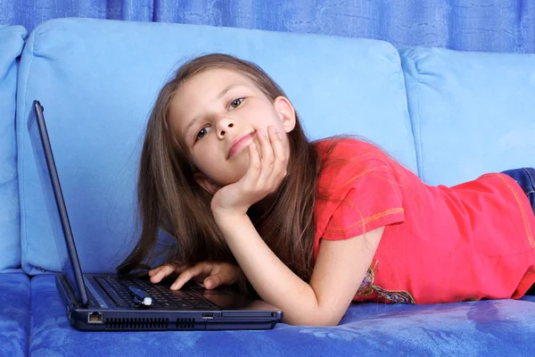 Девушка с компьютером дома в диване — стоковое фото