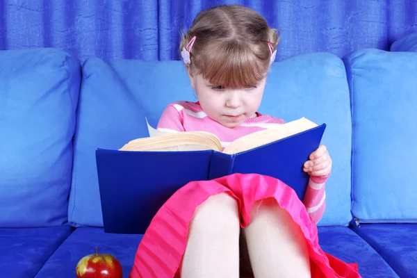 Chica libro de lectura con manzana en el sofá —  Fotos de Stock