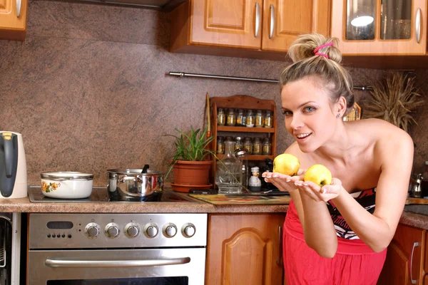 Mulher segurando duas maçãs na cozinha — Fotografia de Stock