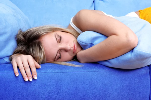Mujer joven durmiendo almohadas en sofá azul — Foto de Stock
