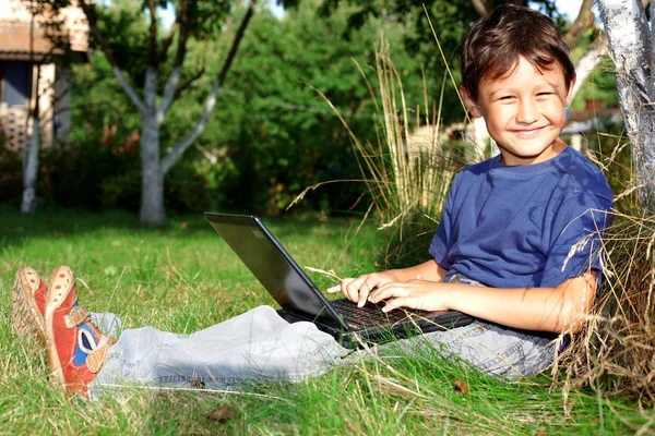 Chlapec s notebookem sedět u stromu venku — Stock fotografie
